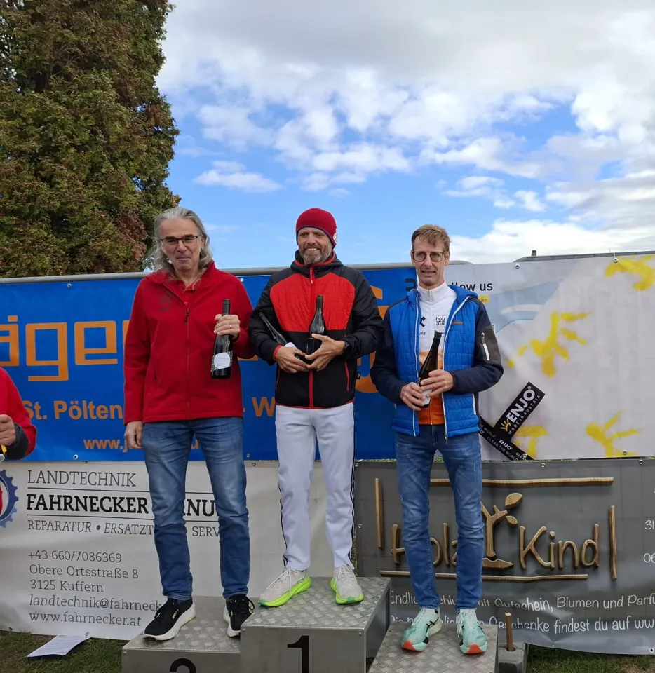 Eine Gruppe von Männern steht mit Flaschen auf einem Podium.