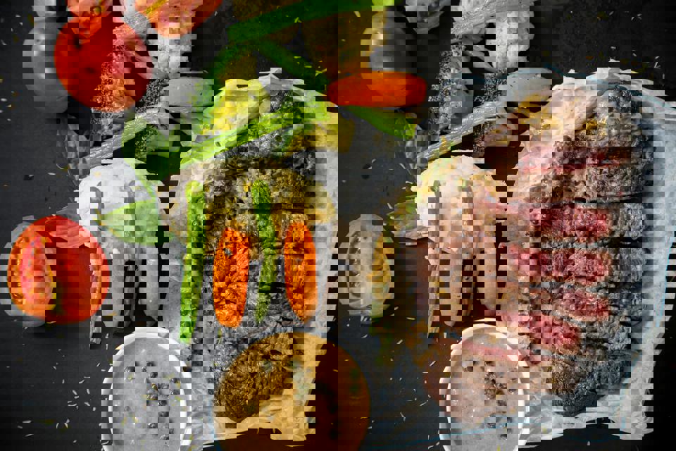 Ein Steak und Gemüse auf einer schwarzen Oberfläche.