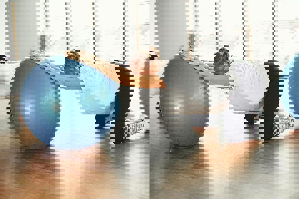 eine Person, die sich auf einem blauen Ball dehnt