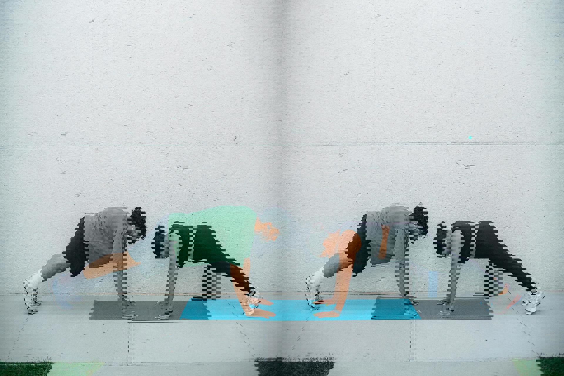 Eine Person und eine andere Person machen Liegestütze auf einer Matte.