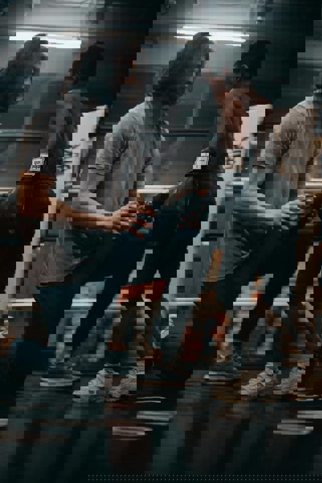 Eine Person kniet auf einem Knie mit einem Kind in einem Boxring.