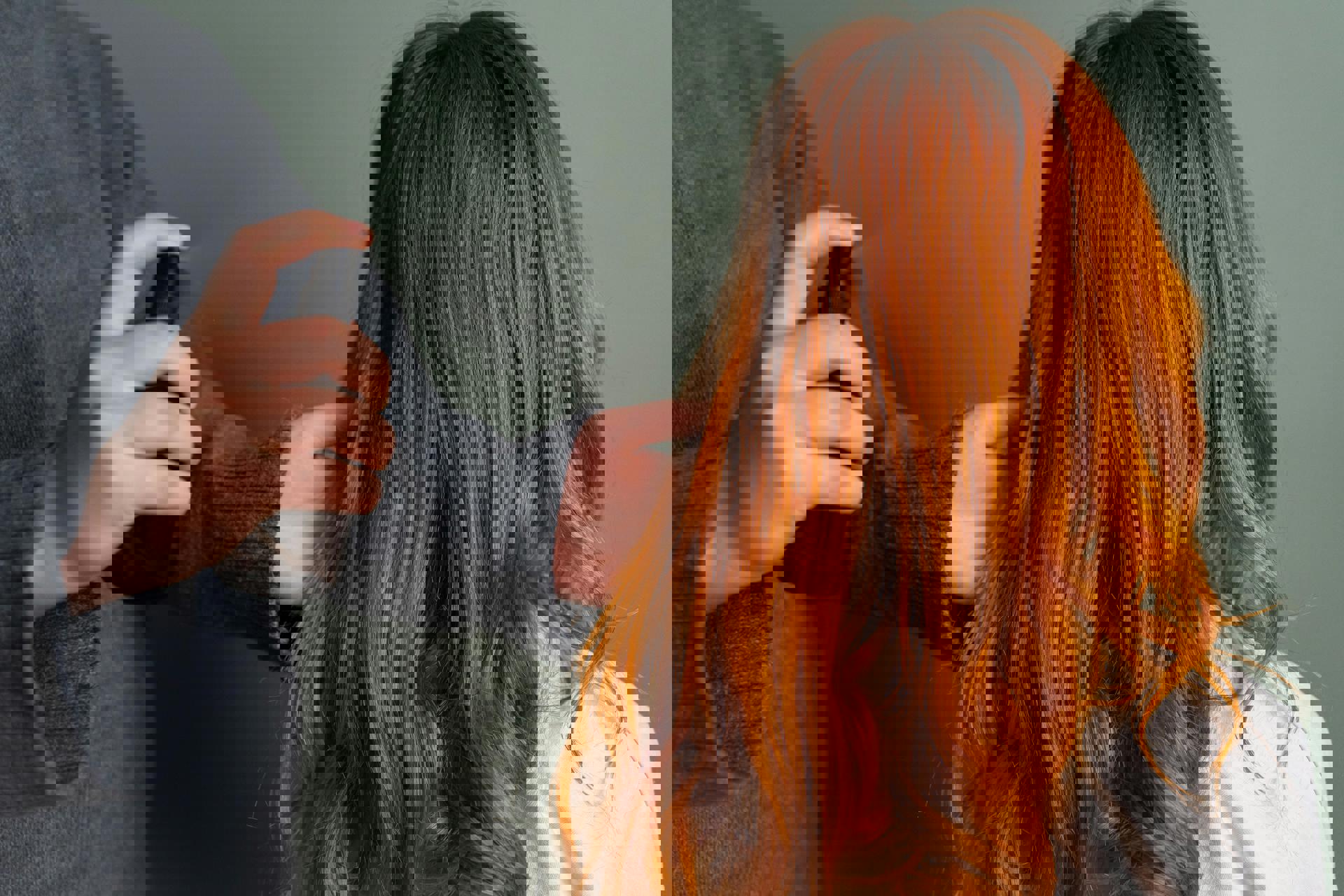 Eine Person sprüht Haarspray auf den Kopf einer anderen Person.