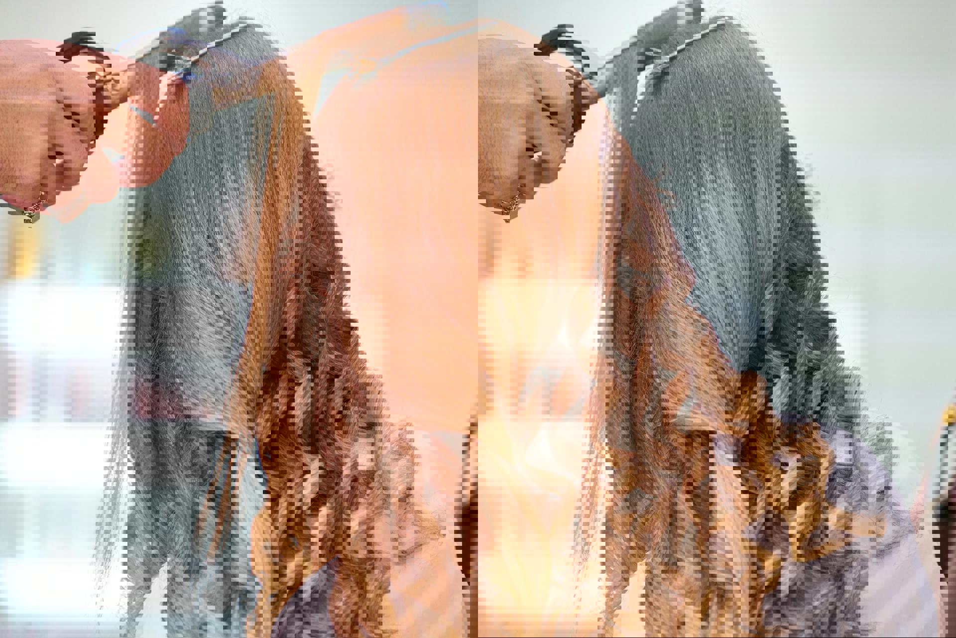 Eine Person, die mit einem Lockenstab Haare stylt.