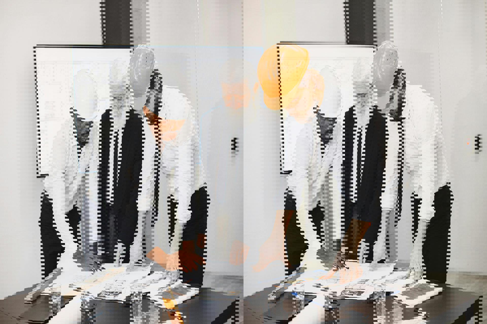 Eine Gruppe von Männern mit Schutzhelmen, die einen Bauplan betrachten.