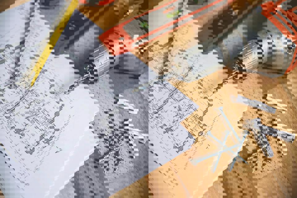 Ein Bohrer auf einem Blatt Papier neben einem Lineal und Schrauben.