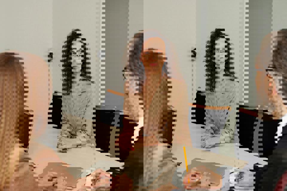 Eine Person sitzt an einem Tisch mit einer Person in einem Notizbuch.