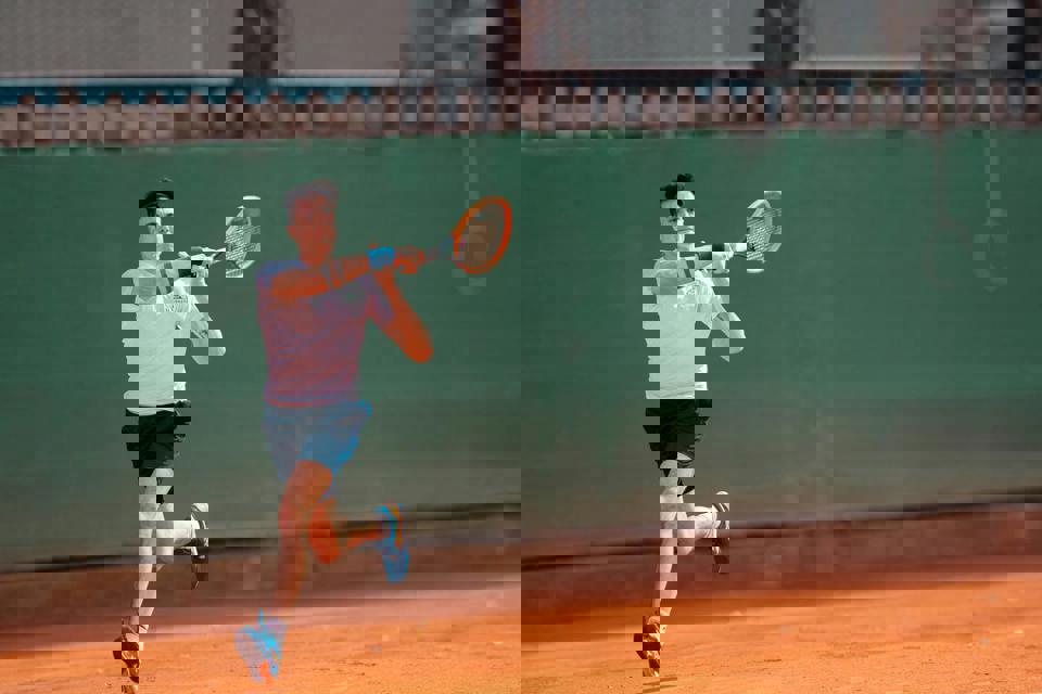 eine Person, die auf einem Sandplatz Tennis spielt