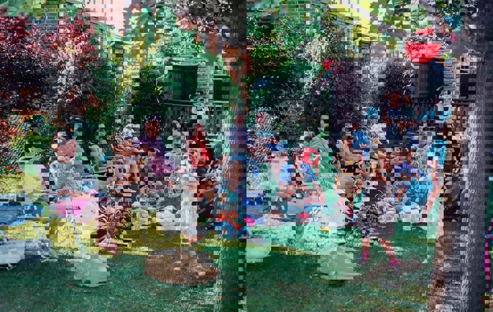 eine Gruppe von Menschen, die auf Stühlen in einem Hof sitzen