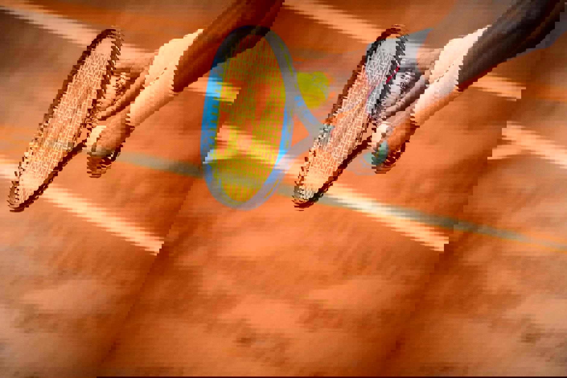 Ein Tennisspieler hält einen Schläger und einen Ball.